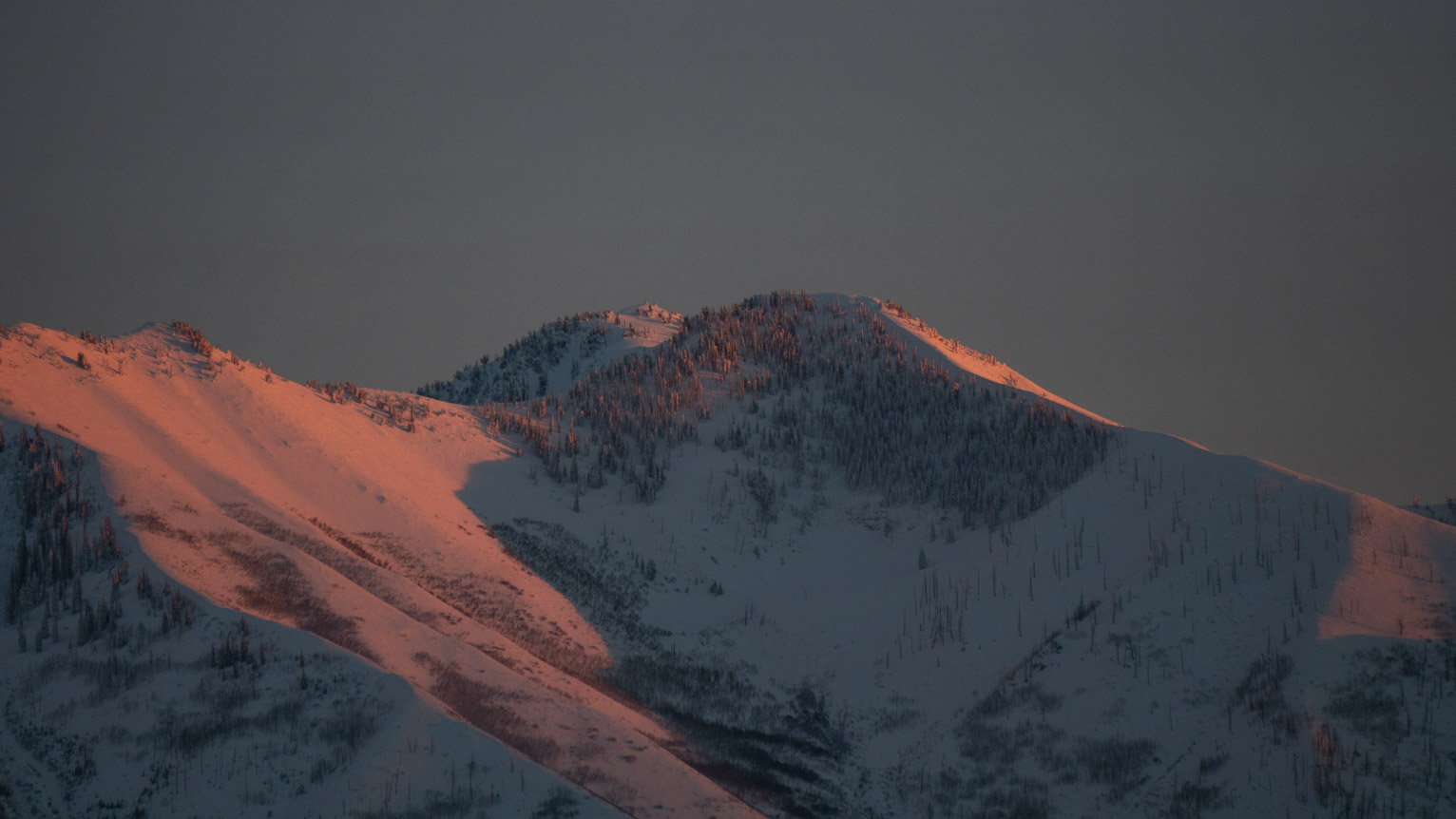 Sunset light hits the blue mountain slopes